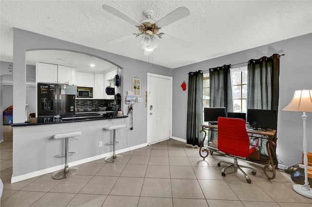 tiled office with a textured ceiling and ceiling fan