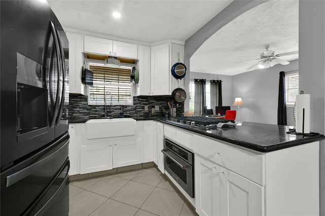 kitchen featuring kitchen peninsula, appliances with stainless steel finishes, white cabinets, and sink