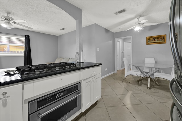 kitchen featuring a textured ceiling, stainless steel appliances, ceiling fan, white cabinetry, and light tile patterned flooring