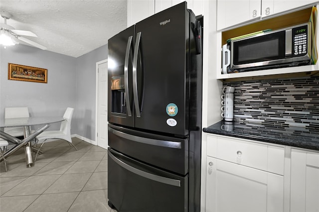 kitchen featuring white cabinets, black fridge with ice dispenser, backsplash, and dark stone countertops