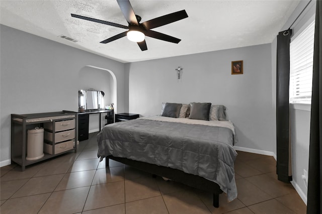 tiled bedroom featuring ceiling fan and a textured ceiling