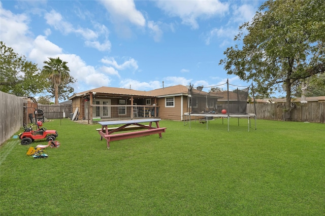 rear view of house with a yard and a trampoline