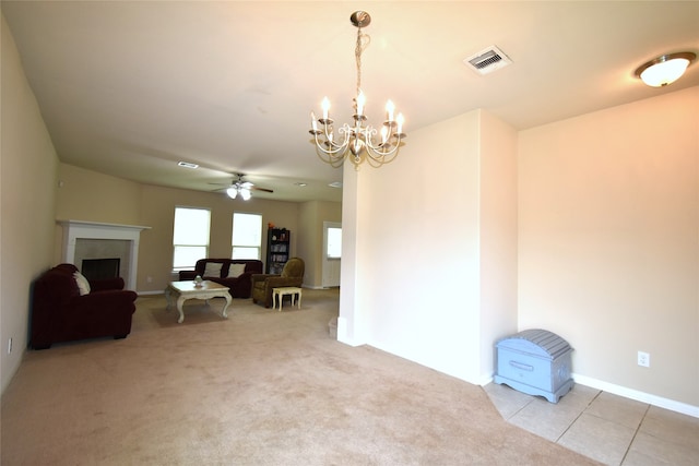 carpeted living room with ceiling fan with notable chandelier