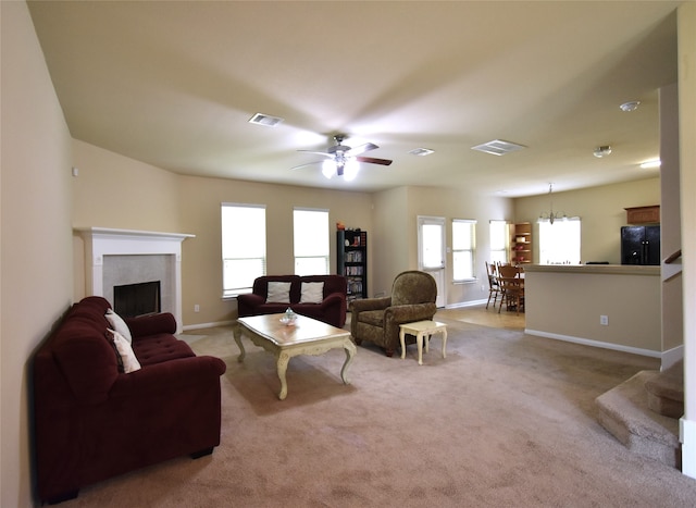 living room with ceiling fan with notable chandelier, a healthy amount of sunlight, and light carpet