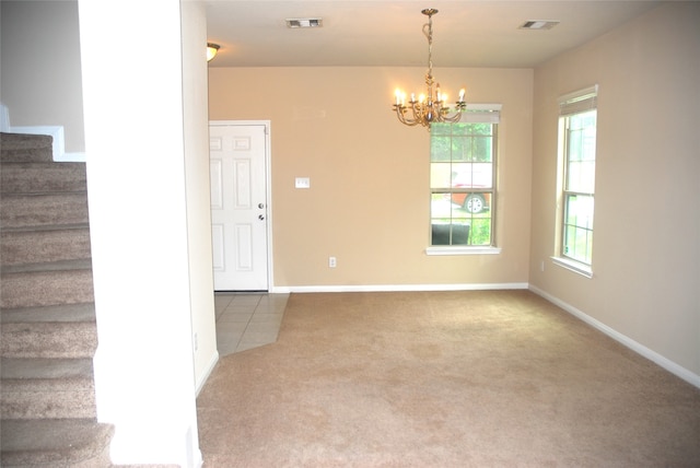 carpeted spare room with an inviting chandelier