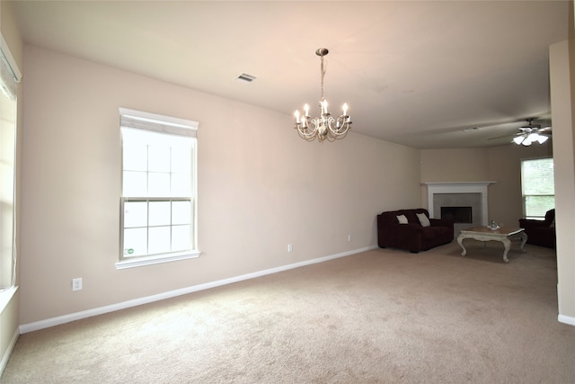 unfurnished living room featuring carpet floors, a healthy amount of sunlight, and ceiling fan with notable chandelier