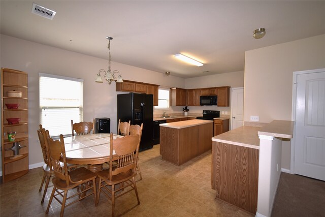 kitchen featuring kitchen peninsula, sink, black appliances, decorative light fixtures, and a notable chandelier