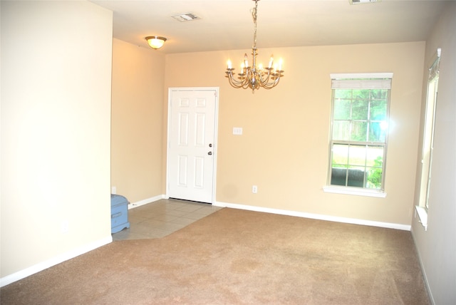 carpeted spare room with a chandelier