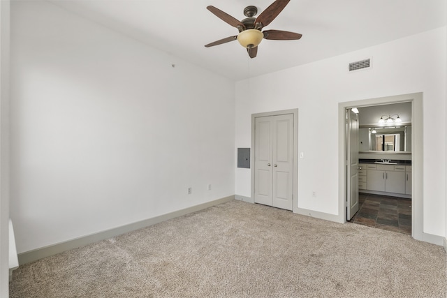 unfurnished bedroom featuring carpet flooring, ensuite bath, ceiling fan, sink, and a closet