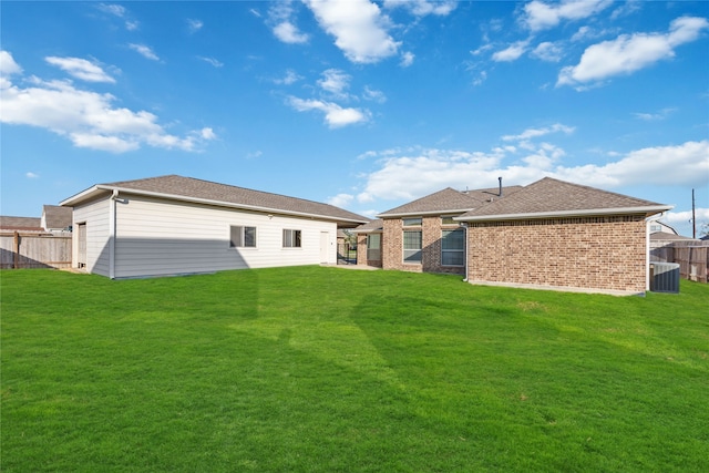 rear view of house with a lawn and central AC