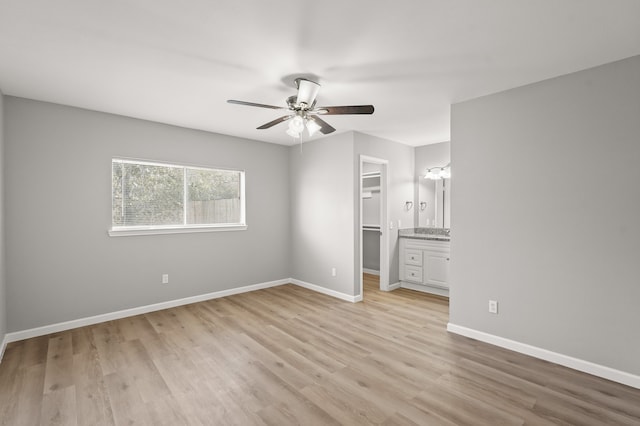 unfurnished bedroom with a closet, a walk in closet, light hardwood / wood-style floors, and ceiling fan