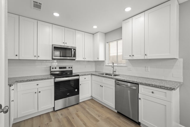 kitchen with stainless steel appliances, white cabinetry, and sink