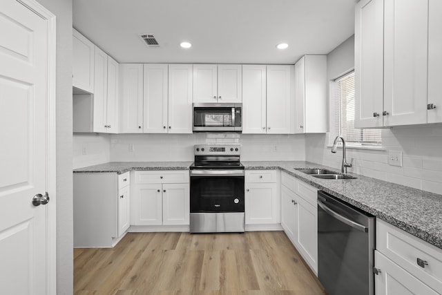 kitchen featuring appliances with stainless steel finishes, light wood-type flooring, white cabinetry, and sink