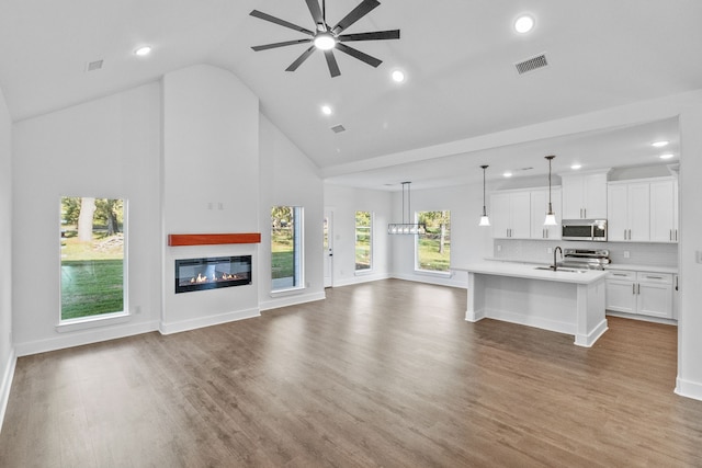 unfurnished living room with hardwood / wood-style flooring, a healthy amount of sunlight, and high vaulted ceiling