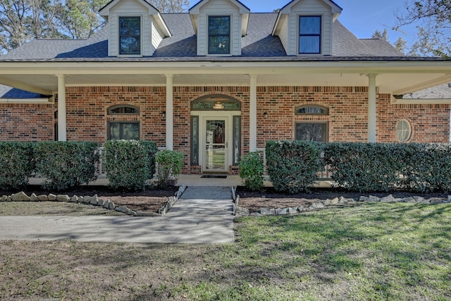 doorway to property with covered porch and a lawn