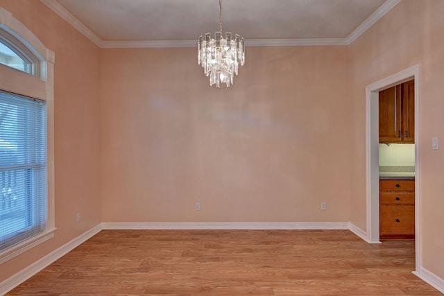 spare room with a notable chandelier, crown molding, and light hardwood / wood-style flooring