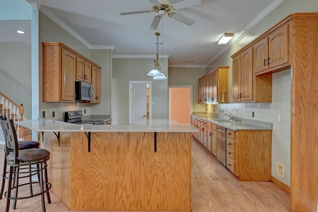 kitchen with light wood-type flooring, stainless steel appliances, ornamental molding, and sink