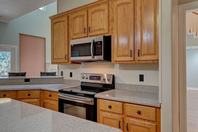 kitchen featuring light stone counters, light hardwood / wood-style floors, and appliances with stainless steel finishes