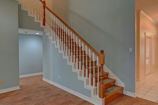 stairs with hardwood / wood-style flooring, ornamental molding, and a high ceiling