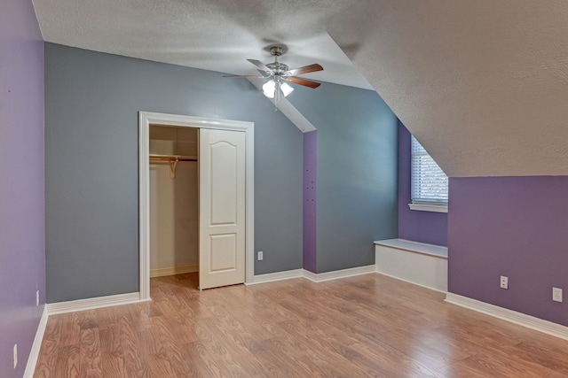 additional living space featuring lofted ceiling, ceiling fan, a textured ceiling, and light wood-type flooring