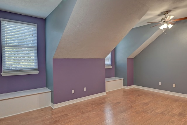 additional living space featuring ceiling fan, light hardwood / wood-style flooring, a healthy amount of sunlight, and vaulted ceiling