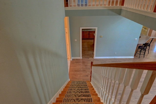 staircase with a towering ceiling and hardwood / wood-style flooring