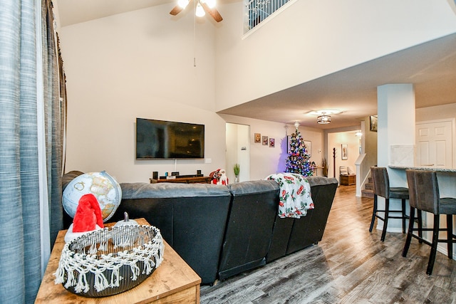 living room with hardwood / wood-style flooring, ceiling fan, and a towering ceiling