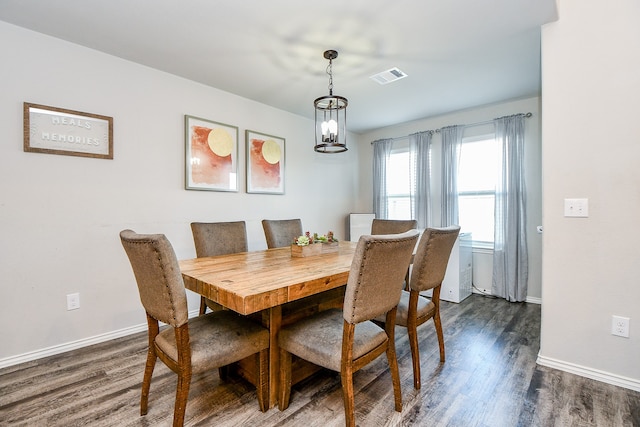 dining area with dark hardwood / wood-style floors and an inviting chandelier