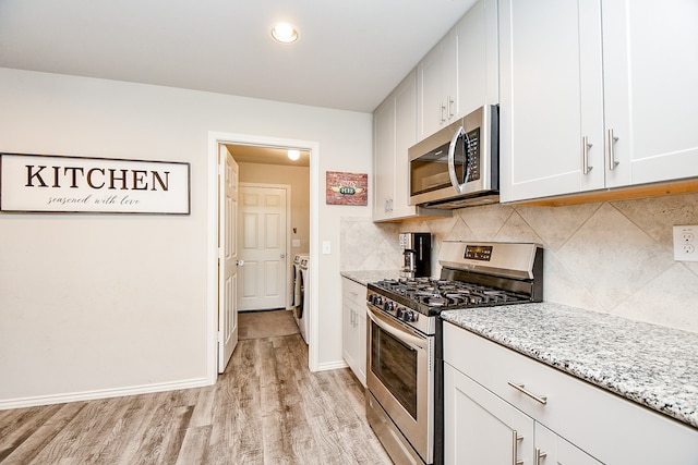 kitchen with washing machine and clothes dryer, white cabinetry, light wood-type flooring, and appliances with stainless steel finishes