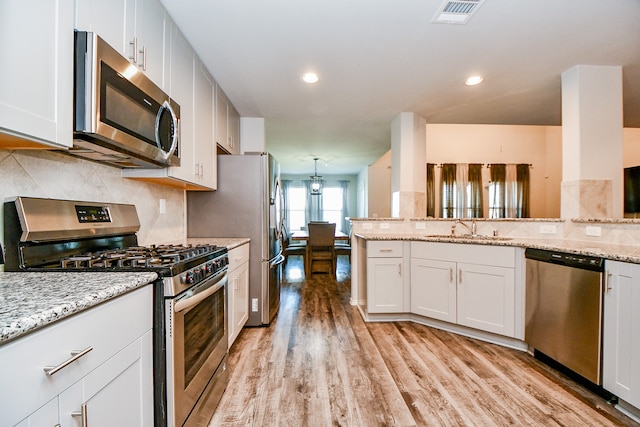 kitchen with white cabinetry, sink, stainless steel appliances, light stone counters, and light hardwood / wood-style flooring