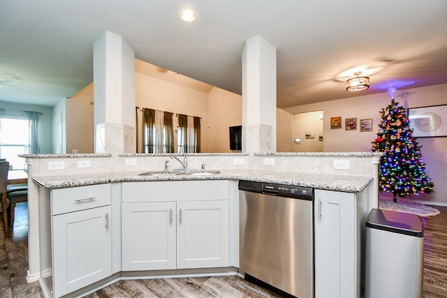 kitchen with kitchen peninsula, white cabinetry, stainless steel dishwasher, and sink