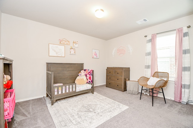 carpeted bedroom featuring a nursery area