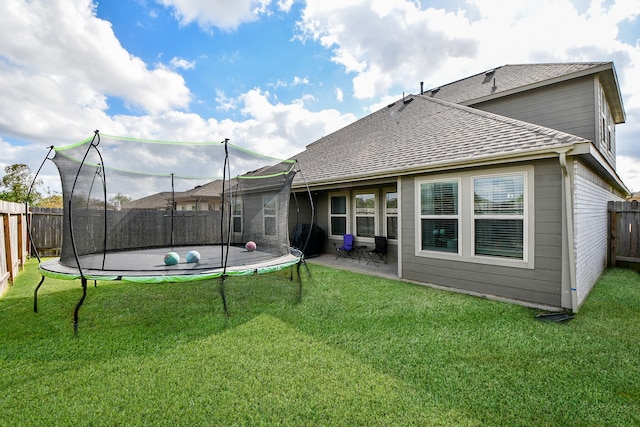 back of property featuring a trampoline, a patio, and a yard