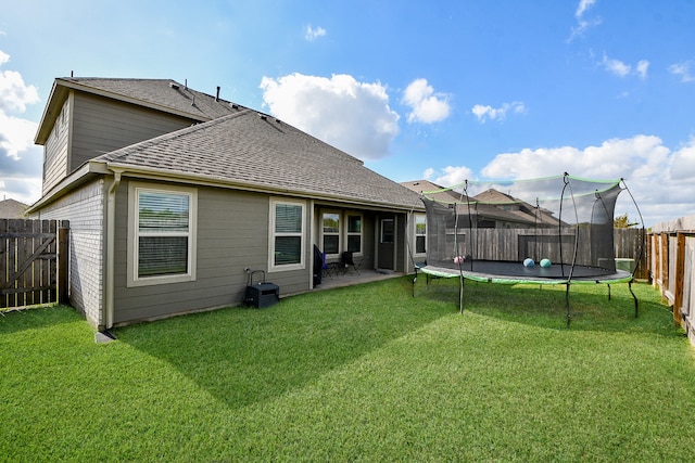 back of property featuring a yard, a trampoline, and a patio