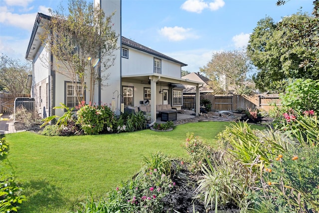 back of property with a lawn, ceiling fan, and a patio