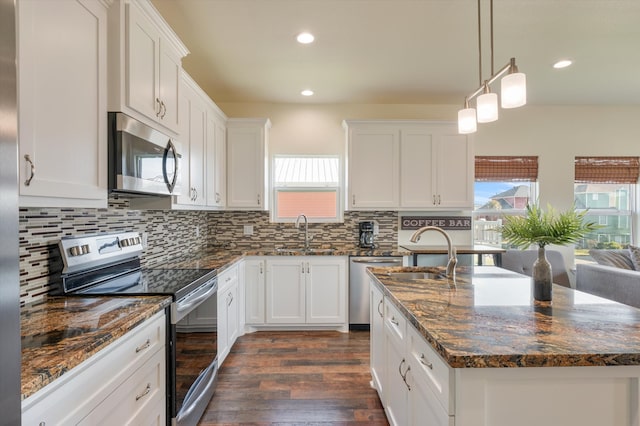 kitchen featuring dark hardwood / wood-style flooring, white cabinetry, a kitchen island with sink, and appliances with stainless steel finishes