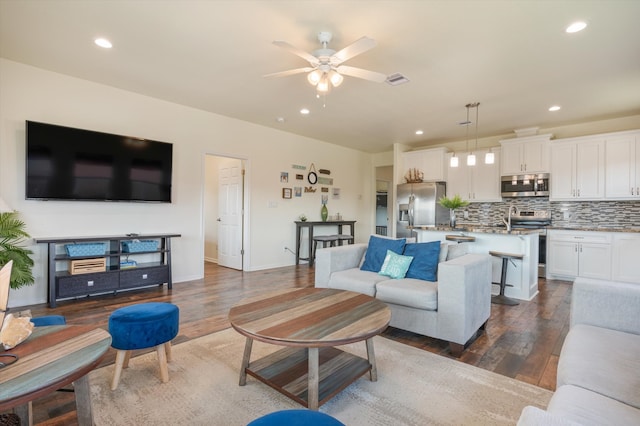 living room featuring ceiling fan and dark wood-type flooring