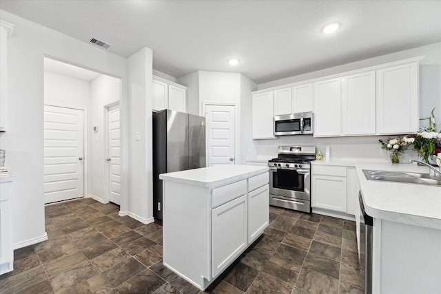 kitchen featuring a kitchen island, white cabinetry, sink, and appliances with stainless steel finishes