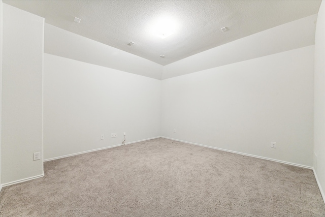 unfurnished room featuring a textured ceiling, light colored carpet, and lofted ceiling