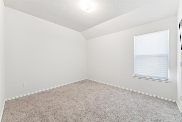 spare room with light carpet and lofted ceiling