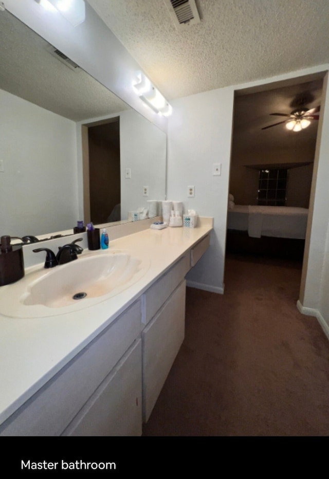 bathroom with vanity, ceiling fan, and a textured ceiling