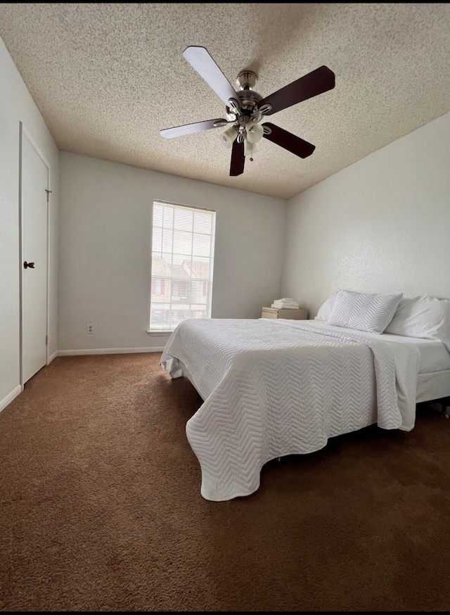 bedroom featuring a textured ceiling, dark carpet, and ceiling fan