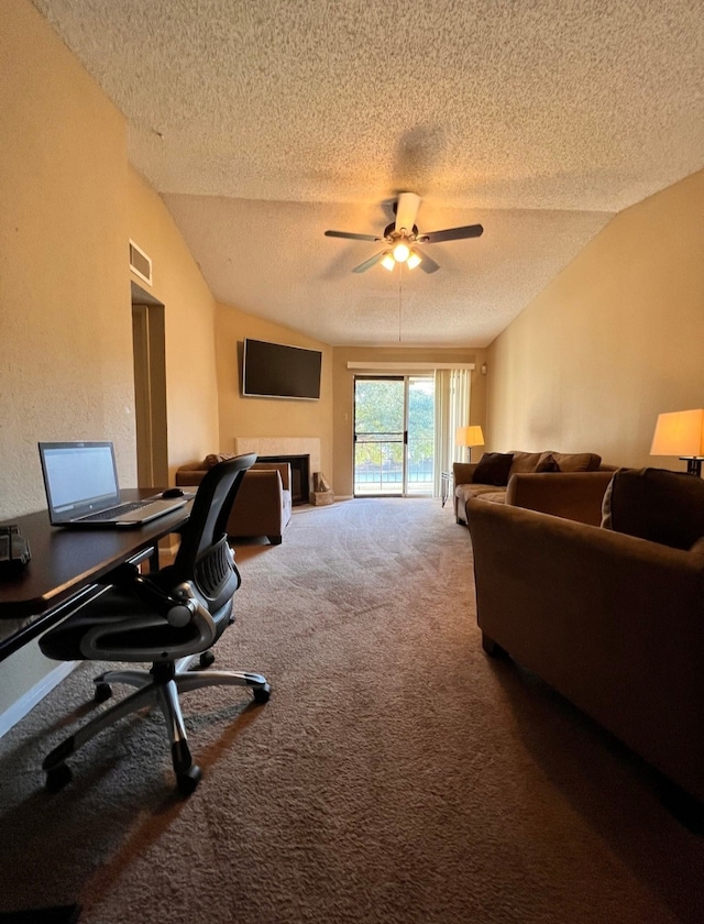 carpeted office space with a textured ceiling, a tile fireplace, ceiling fan, and lofted ceiling