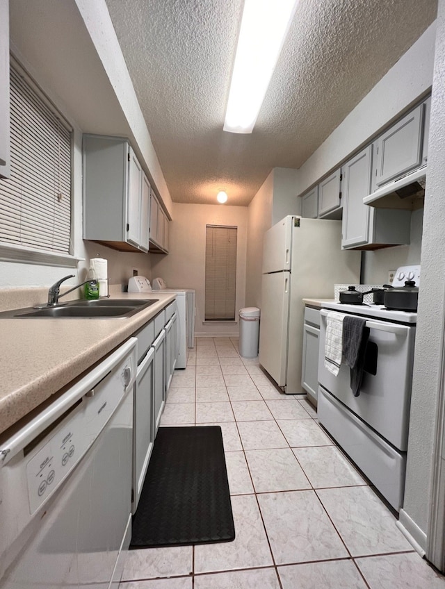 kitchen with sink, a textured ceiling, white appliances, gray cabinets, and light tile patterned floors