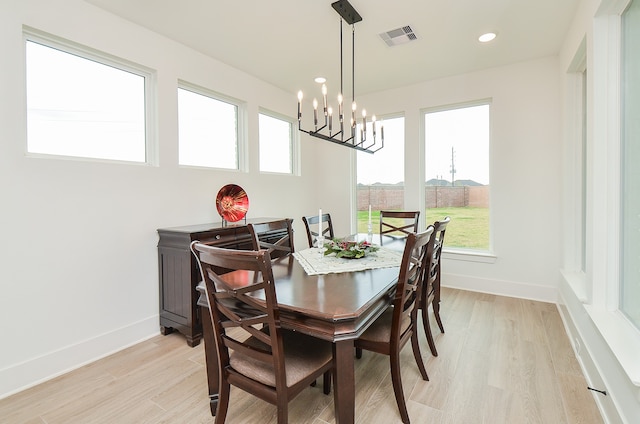 dining area with a chandelier, a wealth of natural light, and light hardwood / wood-style flooring