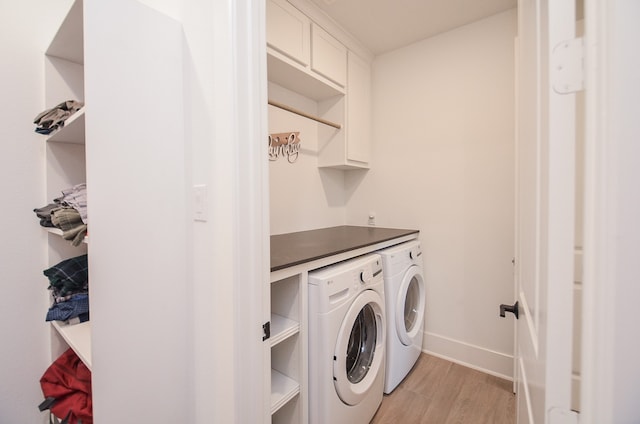 washroom with cabinets, light hardwood / wood-style flooring, and washing machine and clothes dryer