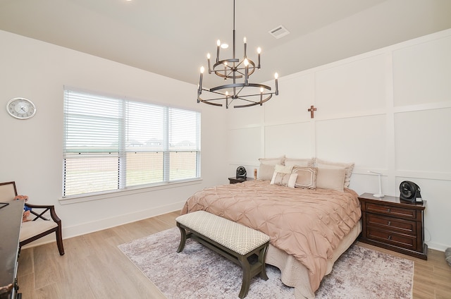 bedroom with light wood-type flooring and an inviting chandelier