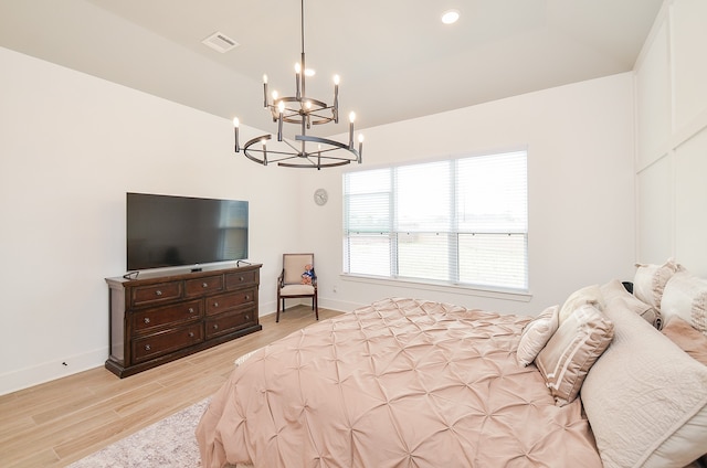 bedroom featuring light wood-type flooring and an inviting chandelier