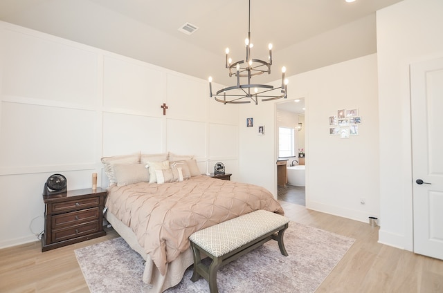 bedroom with a chandelier, light hardwood / wood-style floors, and ensuite bath