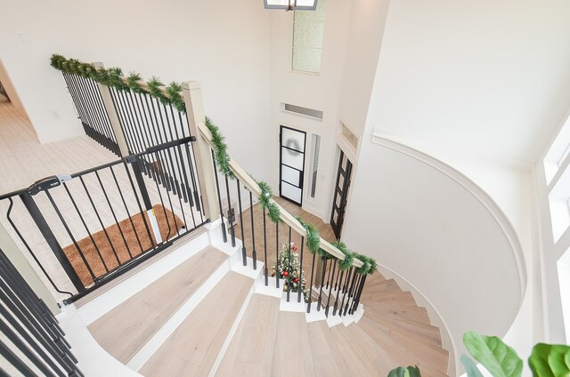 stairs featuring hardwood / wood-style floors and a high ceiling